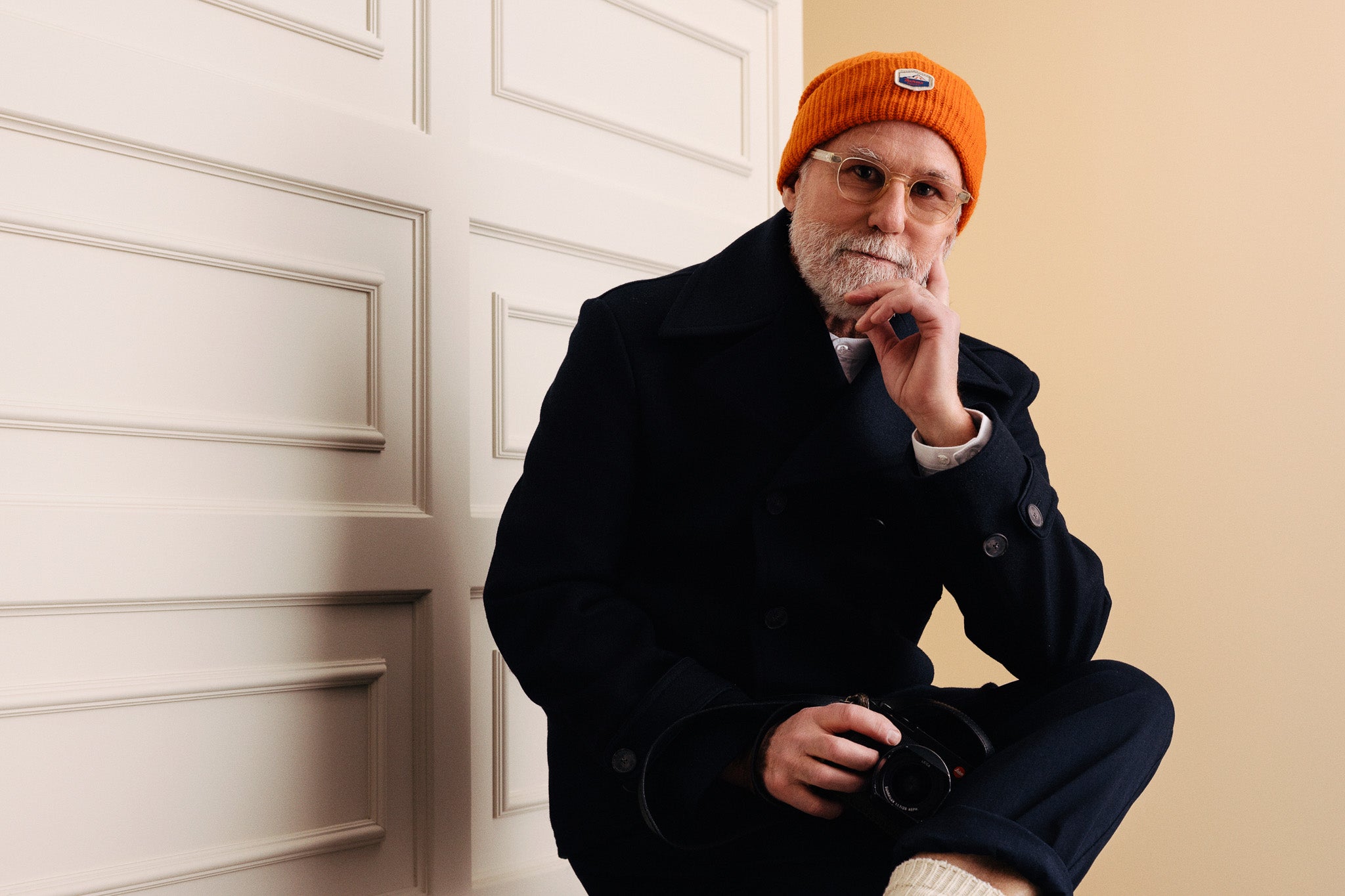 Maður í bláum sjóarajakka, peacoat, með appelsínugula húfu úr ull.