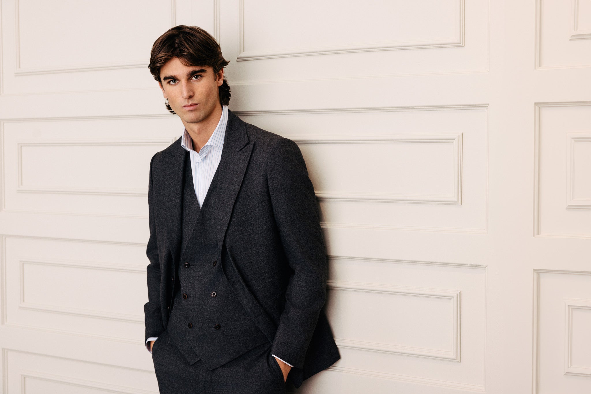 Herramaður í vönduðum, steingráum jakkafötum og teinóttri skyrtu.